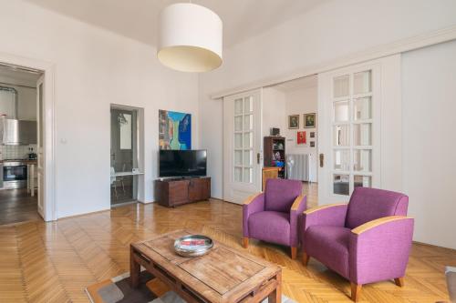 - un salon avec deux chaises violettes et une table basse dans l'établissement Sunny, Airy, Artsy & Authentic Loft with Balcony, à Budapest