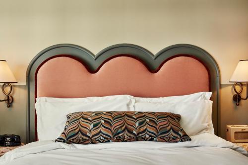 a bed with a large red headboard and a pillow at The Hoxton, Charlottenburg in Berlin