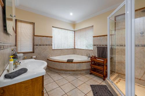 ein großes Bad mit einer Badewanne und einer Dusche in der Unterkunft Mhlati Guest Cottages in Malelane