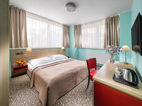 プラハにあるホテル ミカエルのベッド、デスク、窓が備わるホテルルームです。