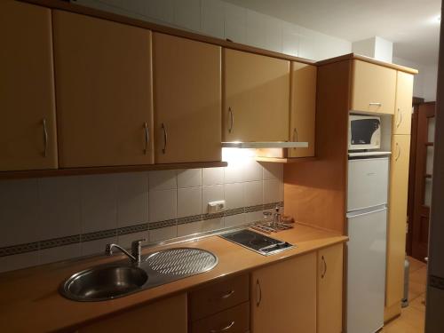 una cucina con armadi in legno, lavandino e frigorifero di Casa Virués a Grazalema