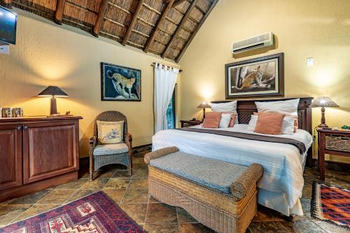 a bedroom with a large bed and a chair at Mhlati Guest Cottages in Malelane