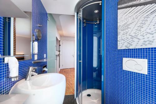 uma casa de banho em azulejos azuis com um lavatório e um chuveiro em Sedartis Swiss Quality Hotel em Thalwil