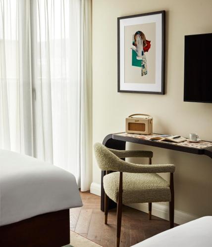 a bedroom with a desk and a chair and a bed at The Hoxton, Charlottenburg in Berlin