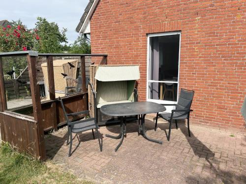 a patio with a table and chairs next to a brick building at Schwalbennest - Fewo 1 in Nordstrand