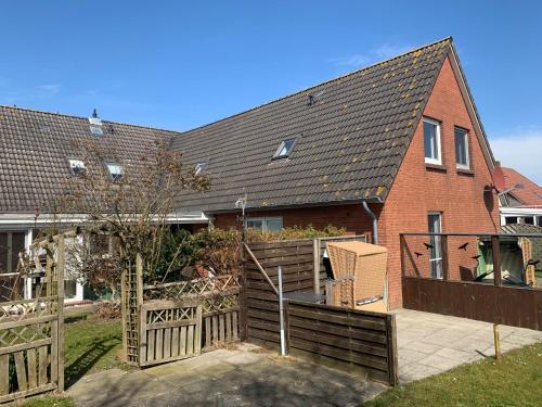 a house with a wooden fence in front of it at Schwalbennest - Fewo 2 in Nordstrand