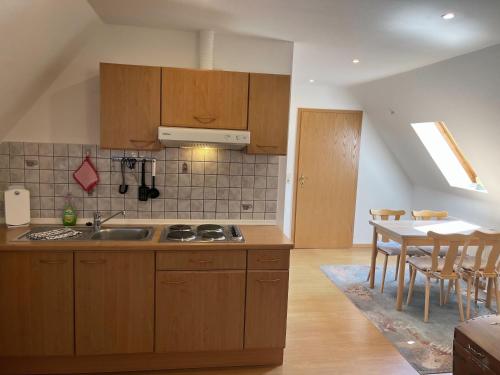 a kitchen with wooden cabinets and a table with chairs at Schwalbennest - Fewo 2 in Nordstrand