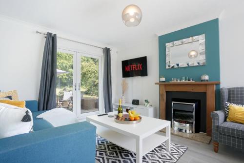 a living room with a blue couch and a table at Detached House - Close to City Centre - Free Parking, Fast Wifi, Private Garden and Smart TV with Netflix by Yoko Property in Milton Keynes