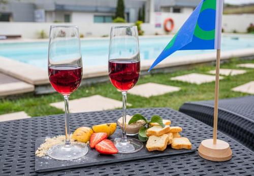 two glasses of wine and food on a table at Furnaka Eco Village in Lourinhã