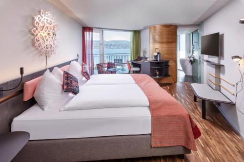 a hotel room with a large bed and a balcony at Sedartis Swiss Quality Hotel in Thalwil