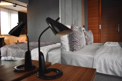 Hotel City View Deluxe في سراييفو: غرفة نوم بسريرين ومصباح على طاولة