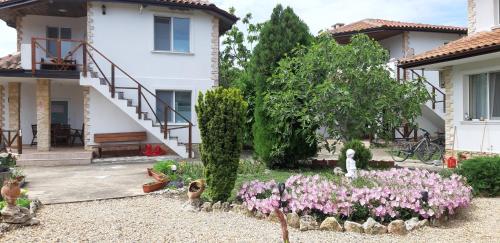 a garden with pink flowers in front of a house at Къща за гости Света Марина in Krapets