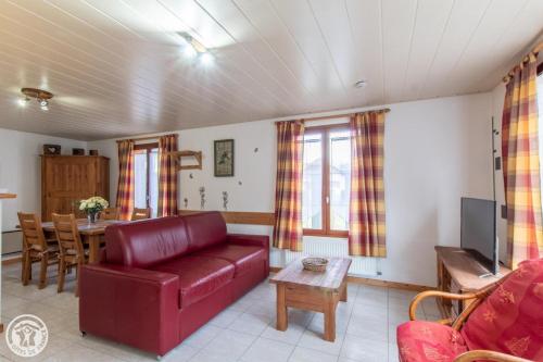 uma sala de estar com um sofá vermelho e uma mesa em Gîte Annecy 06 - Au Royaume des Marmottes - Appt 06 em Doussard