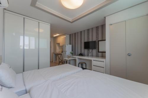 1 dormitorio con cama blanca y escritorio en Staywell Hotel, en Busan