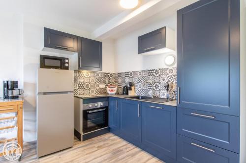a kitchen with blue cabinets and a white refrigerator at Gite Annecy 102 - Au Royaume des Castors - STUDIO 102 in Doussard