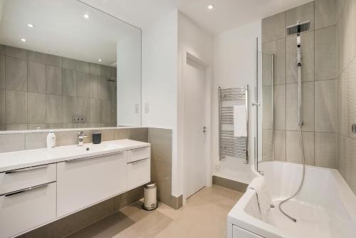 La salle de bains blanche est pourvue d'un lavabo et d'une douche. dans l'établissement StayLux Kensington, à Londres