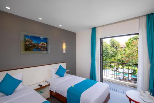 a hotel room with two beds and a window at ÊMM Hotel Hoi An in Hoi An