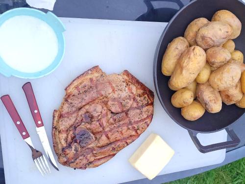 a table with a plate of food and a pan of meat and potatoes at Apartmány Nad rybníky in Horní Planá