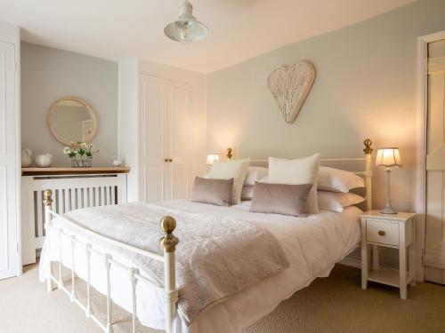 a bedroom with a white bed with a heart on the wall at High Pump Cottage in Chipping Campden