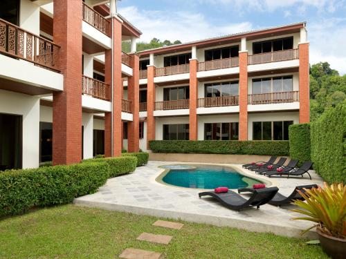 an apartment building with a swimming pool and lounge chairs at Sun Hill Hotel Patong in Patong Beach