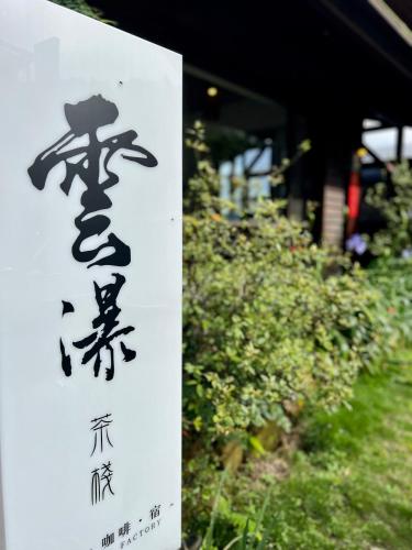 a sign with asian writing on it next to some bushes at Yun pu cha jan in Fanlu