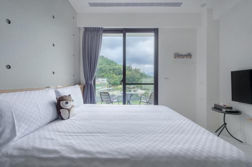 a bedroom with a white bed with a teddy bear on it at 奈斯窩客 l 湖景房 l 含早餐 in Shui-wei