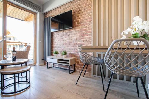 a living room with a table and chairs and a brick wall at Apartamenty Royal Resort & Spa in Zakopane