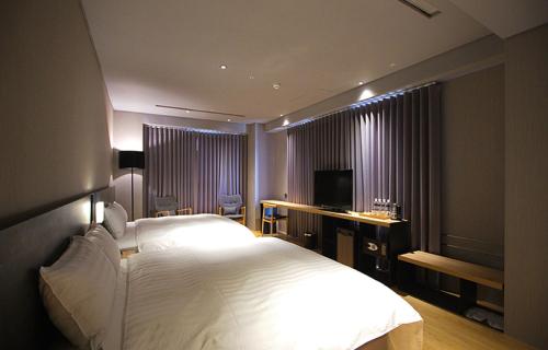 a bedroom with a large white bed and a television at Chiayi Guanzhi Hotel in Chiayi City