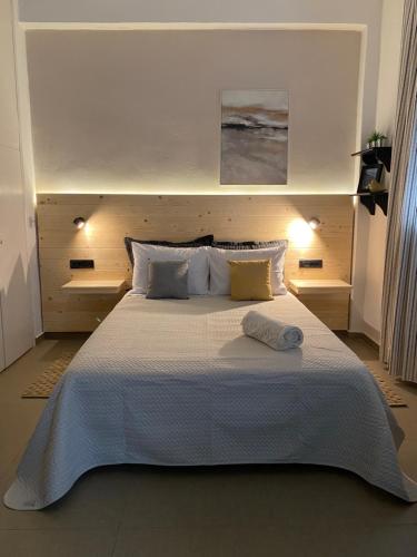 una camera da letto con un letto grande con lenzuola e cuscini bianchi di Tiny Square a Nafpaktos