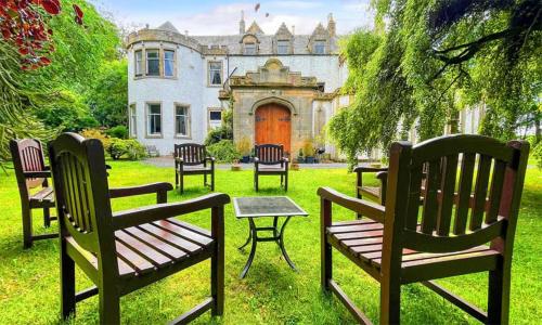 un gruppo di sedie seduti di fronte a una casa di Harvieston Hall a Gorebridge