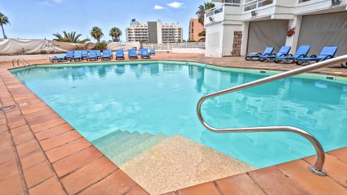 a swimming pool at a hotel with blue chairs at Modern Studio with a Sea View and Pool Access Ponderosa 801 in Playa de las Americas