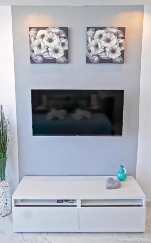 a white living room with a fireplace with three pictures on the wall at Modern Studio with a Sea View and Pool Access Ponderosa 801 in Playa de las Americas