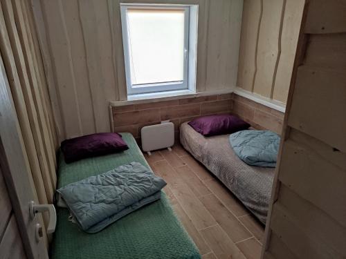 2 camas en una habitación pequeña con ventana en Sodyba Valdo kubilas, en Trakai