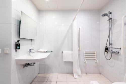 a white bathroom with a sink and a shower at Premier Inn Frankfurt City Centre in Frankfurt