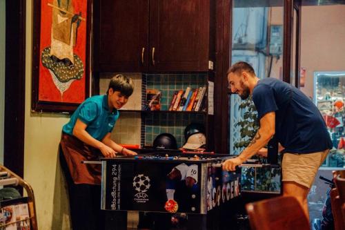 two men standing around a table playing a game at Drift Backpackers Hostel in Hanoi