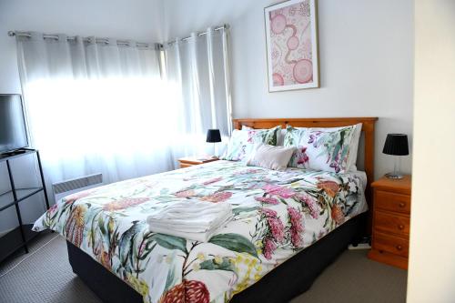 a bedroom with a bed with a floral comforter at Curnows in Bendigo