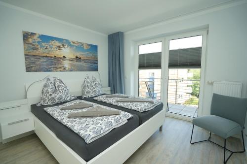 a bedroom with a bed and a chair and a window at Seeblick - a57219 in Cuxhaven