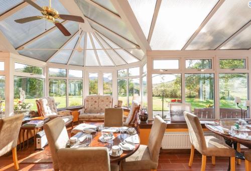 a conservatory with tables and chairs and windows at Killean Farmhouse B&B in Inveraray
