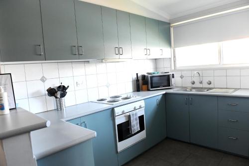 a kitchen with blue cabinets and a stove and microwave at Curnows in Bendigo