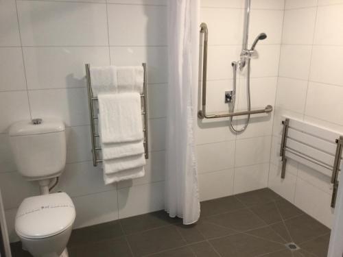 een badkamer met een toilet, een douche en handdoeken bij East Pier Hotel in Napier