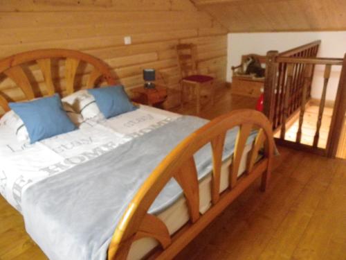 a wooden bed with blue pillows in a room at La Bastide de la Reine Margot in Beaumont