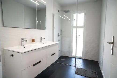 een witte badkamer met een wastafel en een douche bij La villa Sirelis piscine et spa in Gujan-Mestras