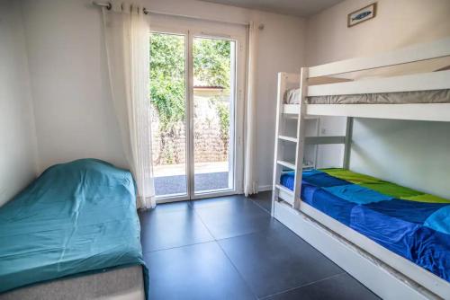 een slaapkamer met 2 stapelbedden en een raam bij La villa Sirelis piscine et spa in Gujan-Mestras