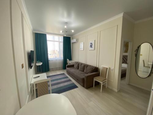un soggiorno con divano e specchio di Alau Apartments a Astana
