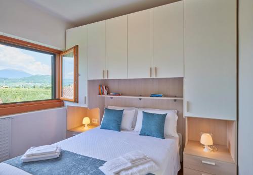 a bedroom with a bed with blue pillows and a window at Appartamento Noal in Bardolino