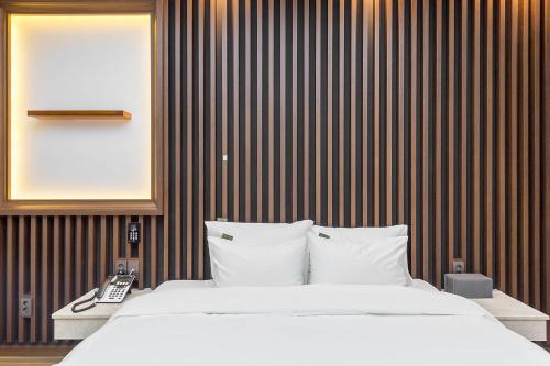 a bedroom with a white bed and a telephone at Hotel Demer Mokpo in Mokpo