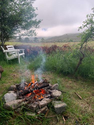 a fire in the grass with a bench in the background at Birkenshaw - Beautiful Shepherd’s Hut in the Highlands. in Dornoch