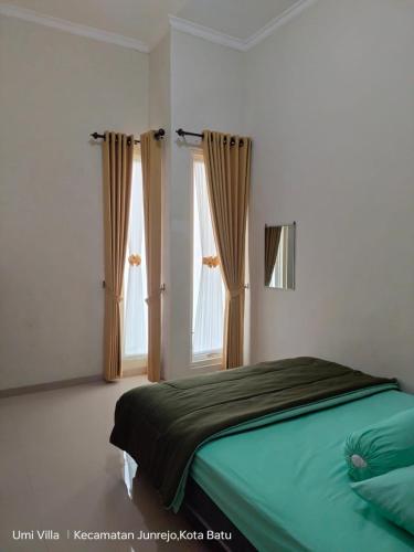 a bedroom with a bed and two windows at Villa Permata Garden Blok D11 Near JTP 3 in Batu