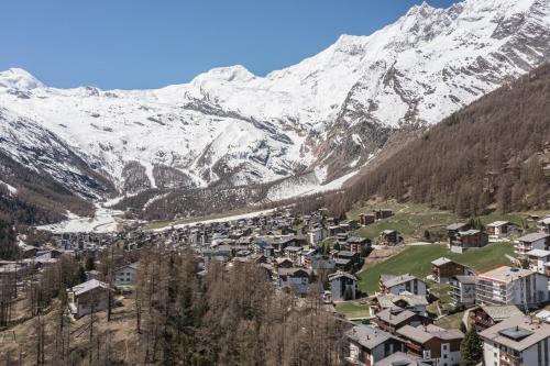 un village en face d'une montagne enneigée dans l'établissement Haus Alfa Studios, à Saas-Fee