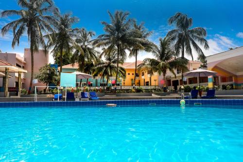 a large swimming pool with palm trees in the background at Mansea Beach Hotel in Kololi